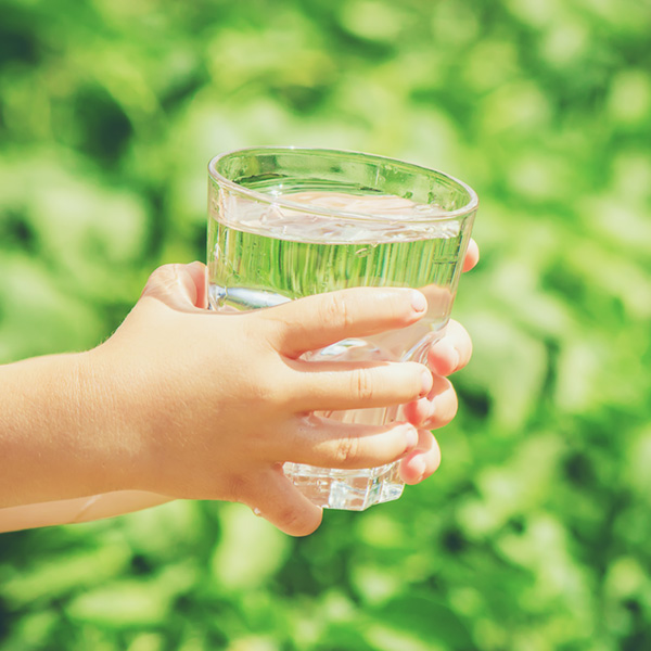 children's hands holding full glass of water