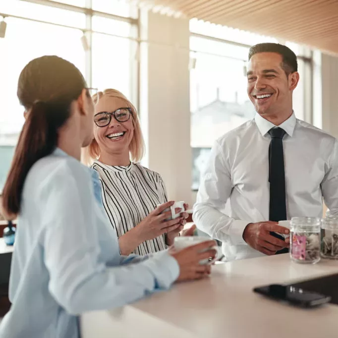 three coworkers conversing in an office breakroom