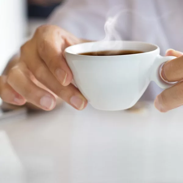 woman holding white mug filled with steaming coffee