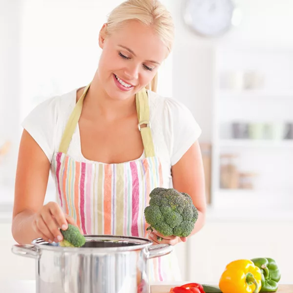woman with apron cooking broccoli