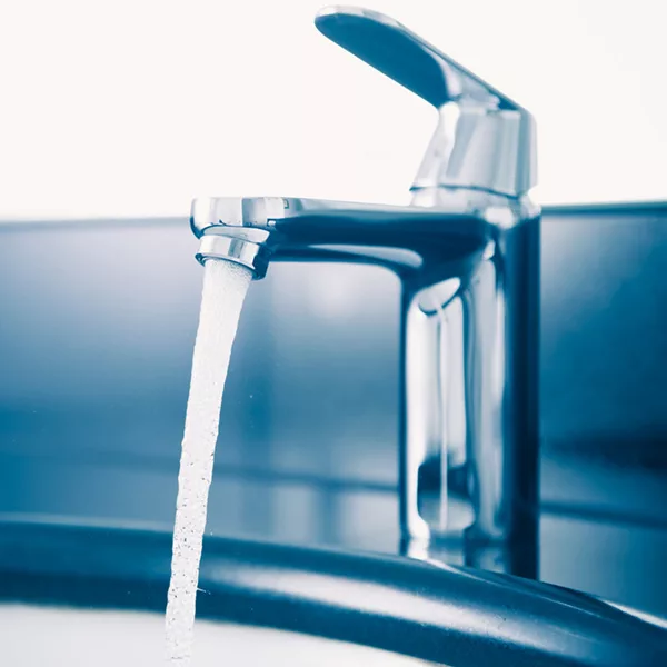 chrome sink faucet spewing stream of water